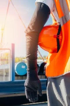 A builder or worker keeps a hard hat on hand. Rear view from the back. Slinger Stock Photos