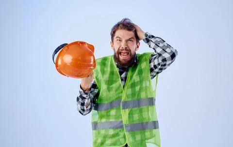 Builder with orange hard hat in hand and reflective vest blue background Copy Stock Photos