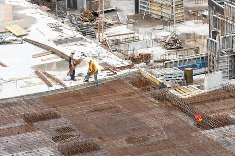 Builder in orange helmet works, construction of multi-storey building or Stock Photos