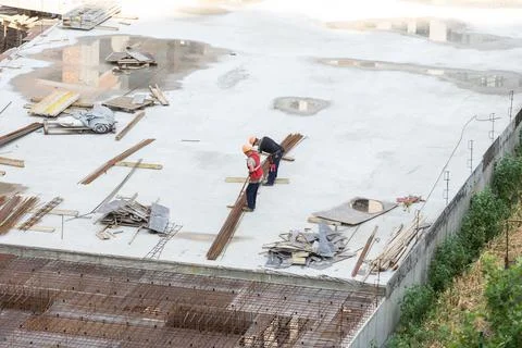 Builder in orange helmet works, construction of multi-storey building or Stock Photos