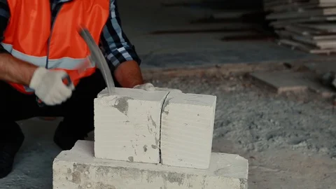 A builder in an orange vest is hammering on a cobblestone. Stock Footage 129194085