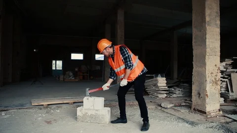 A builder in an orange vest hits the cobbles with a hammer. Stock Footage 129056197