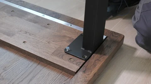 Builder in overalls screwing table legs using a screwdriver Stock Footage 170045931