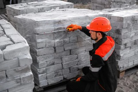 Builder packs bricks into pallets at construction site Foto stock