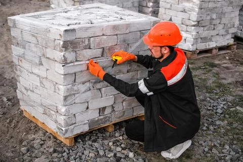 Builder packs bricks into pallets at construction site Stock-Fotos