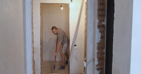 Builder painter whitens walls in new apartment, paint roller on long stick Stock Footage 129836849