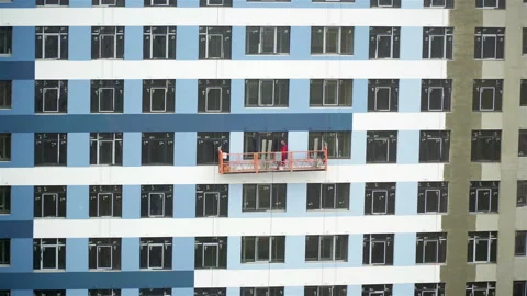 Builder paints the facade of a building at a construction site Stock Footage 105536748