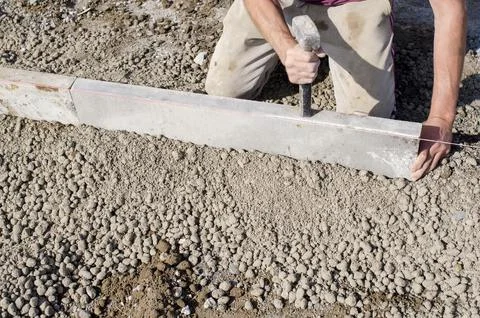 Builder placing edging pin kerb on semi-dry concrete using a string line to.. Stock Photos