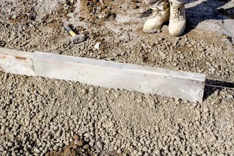 Builder placing edging pin kerb on semi-dry concrete using a string line to.. Stock Photos