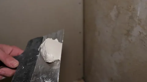 A builder plasterer applies putty or plaster to a trowel during renovation work. Stock Footage 261508176