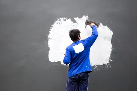 Builder plastering grey concrete at wall with white plaster Stock Photos