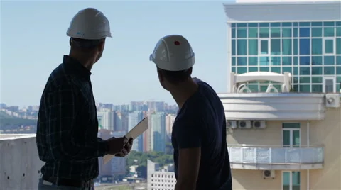 Builder points at the penthouse near the building under construction Stock Footage 68065373