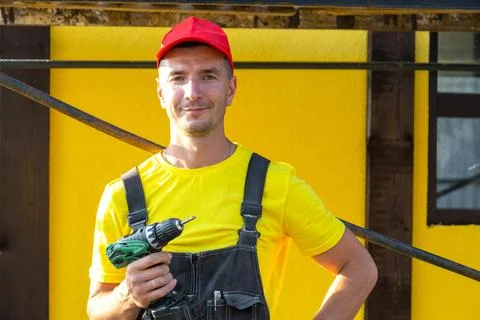 Builder portrait holding drill, standing near house under construction, rep.. Stock Photos