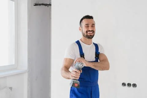Builder posing with a drill in his hands and smiling Stock Photos