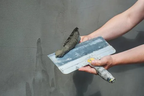 The builder put mortar on the wall. Plaster walls. Exterior finish. Stock Photos