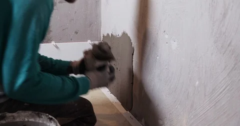 Builder put on wall in bathroom an adhesive mortar for laying tiles, thick layer Stock Footage 129839814