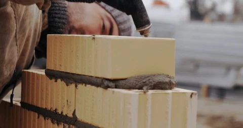 Builder puts brick on cement glue. Worker checks quality of work with level. Stock Footage 128939244