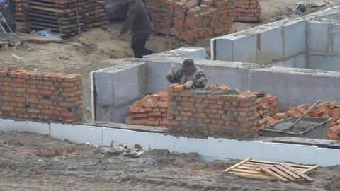 The builder puts a brick wall.  builders are building a housing complex Video stock 120673816