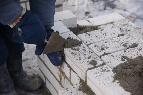 The builder puts bricks in cement mortar. Stock Photos