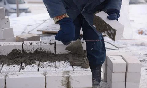 The builder puts the bricks in the cement mortar. Stock Photos