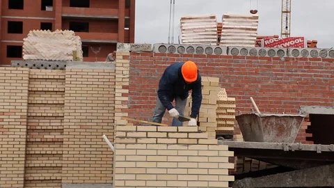 Builder puts the bricks on concrete, for evenness he uses a rope, he beats a Stock Footage 115329847