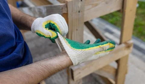 A builder puts on construction gloves to protect his hands. A man puts on wor Stock Photos