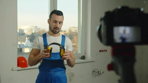 Builder puts on headphones and talks on camera Stock Footage 124846336