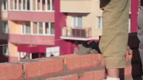 The builder puts the mortar on a brick, then covers it with another brick Stock Footage 117661416