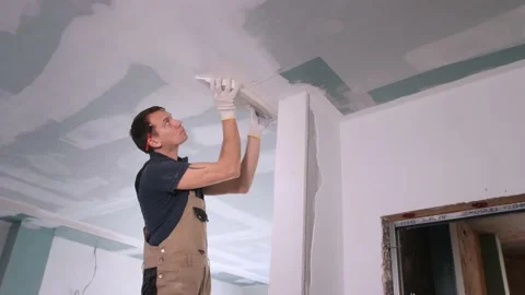 Builder puts plaster on ceiling in room with empty doorway Stock Footage 151784569