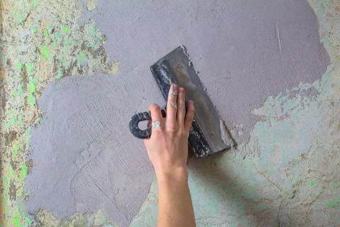 The Builder puts plaster on the wall.Hand holding a spatula with construction Stock Photos
