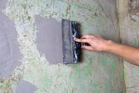 The Builder puts plaster on the wall.Hand holding a spatula with construction Stock Photos