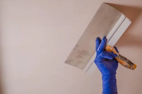 The Builder puts plaster on the wall.Hand holding a spatula with construction Stock Photos