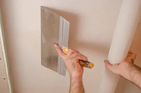 The Builder puts plaster on the wall.Hand holding a spatula with construction Stock Photos