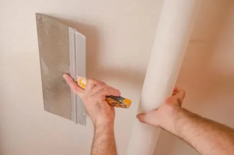 The Builder puts plaster on the wall.Hand holding a spatula with construction Stock Photos
