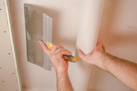 The Builder puts plaster on the wall.Hand holding a spatula with construction Stock Photos