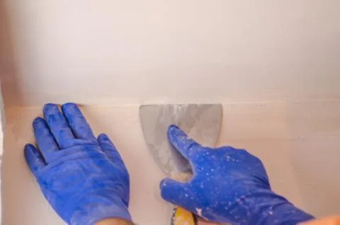 The Builder puts plaster on the wall.Hand holding a spatula with construction Stock Photos