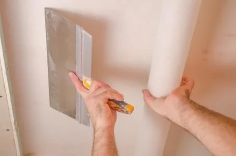 The Builder puts plaster on the wall.Hand holding a spatula with construction Stock Photos
