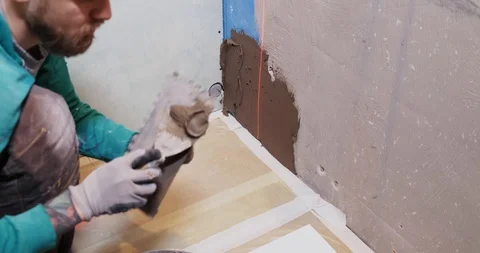 Builder puts tile adhesive on wall to stick ceramic tiles. Repair in bathroom Stock Footage 128958655