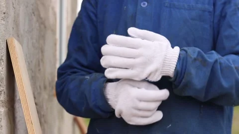 A builder puts on white work gloves Stock Footage 334625041
