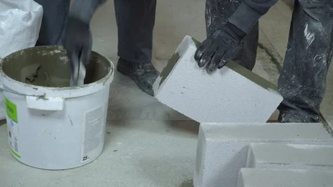 Builder putting mortar on sides of blocks with spatula Stock Footage 104913793