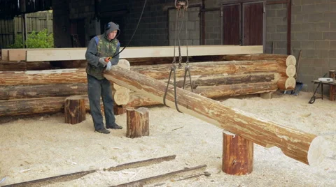 Builder raises wooden timber with Overhead Winch Crane. A man holds a log and Stock Footage 69037062