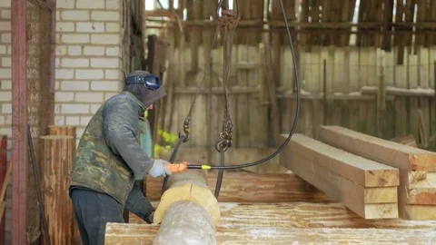 Builder raises wooden timber with Overhead Winch Crane. A man holds a log and Stock Footage 70139079