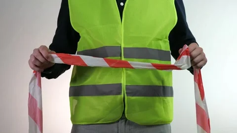 A builder with a red and white tape to fence off the area. A builder in a Stock Footage 314258204