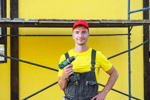 Builder in red cap holding electric drill, maintenance works, home improvem.. Photos