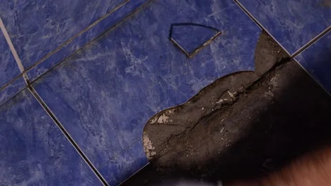 The builder removes the broken tiles from the floor with his hands. Stock Footage 171447325