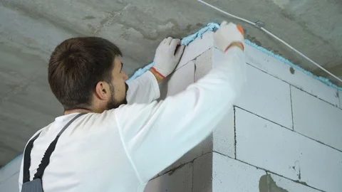 Builder removing excessive mounting foam between wall and ceiling Stock Footage 102889527