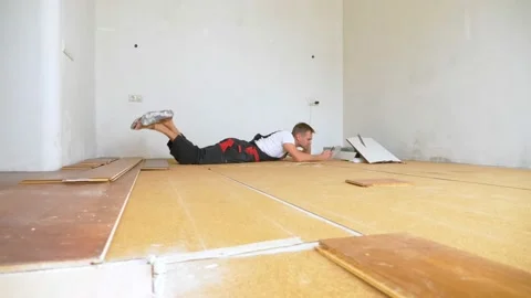 Builder in renovated room lying on floor using smartphone Stock Footage 146331755