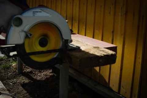 Builder saws a board with a circular saw in the cutting a wooden plank Stock Photos