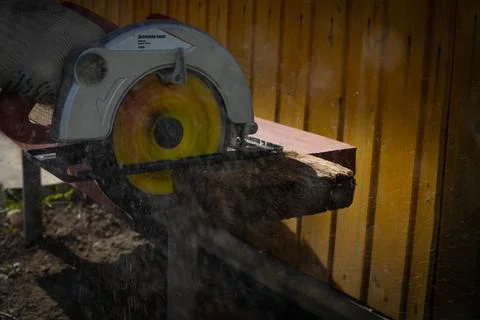 Builder saws a board with a circular saw in the cutting a wooden plank Stock Photos