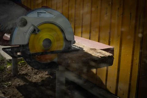 Builder saws a board with a circular saw in the cutting a wooden plank Stock Photos